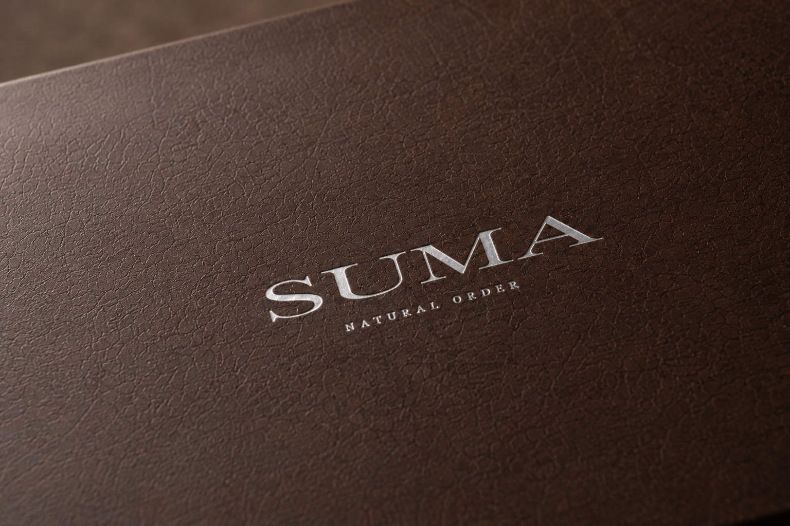 SUMA embossed wordmark on brown leather packaging