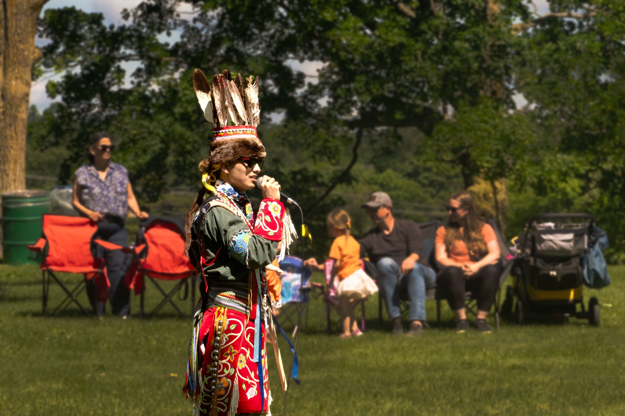 Indigenous participant speaking into a microphone during an outdoor cultural event